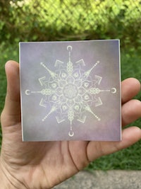a person holding a card with an image of a mandala