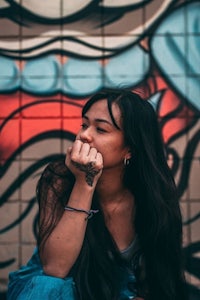 a woman sitting in front of a graffiti wall