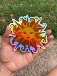 a person holding a sun sticker in their hand