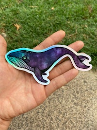 a person holding a blue and purple whale sticker